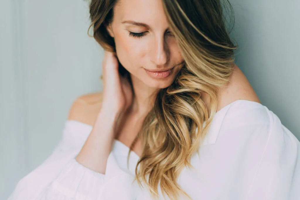 Woman touching hair and looking down with full lips