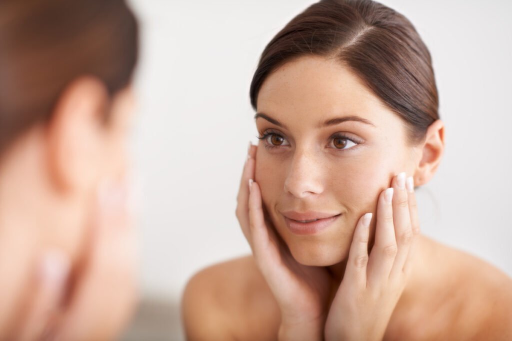 Woman smiling and looking at skin in the mirror